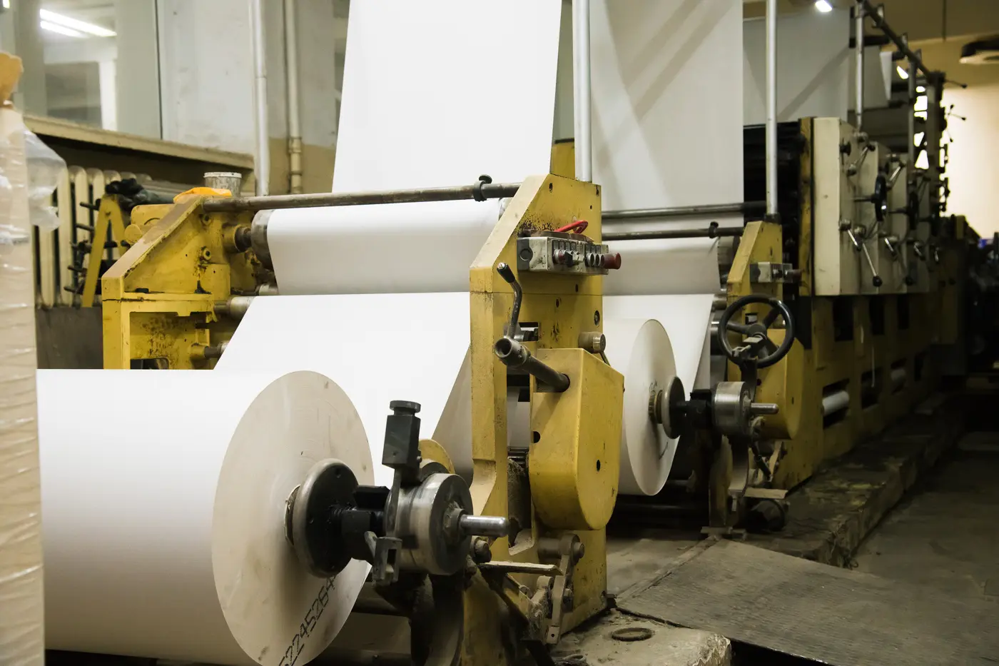 Rolls of newsprint feeding a newspaper printing press